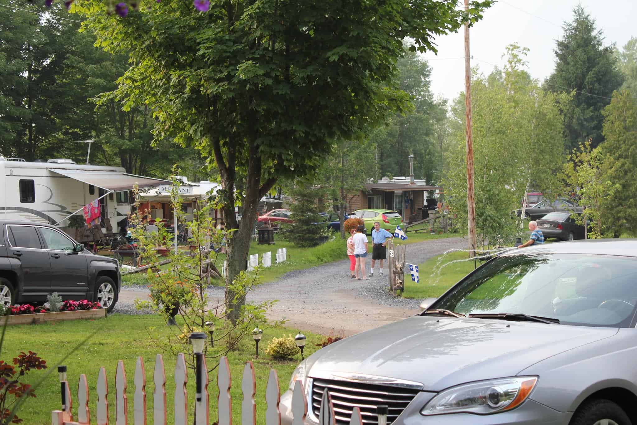Camping avec voitures et personnes discutant accompagnées de drapeaux.